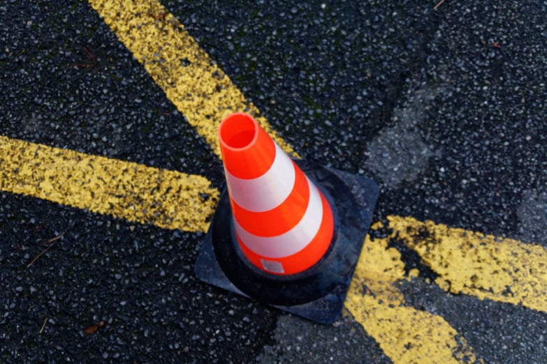 Cône de signlisation sur la route avec bandes jaunes travaux
